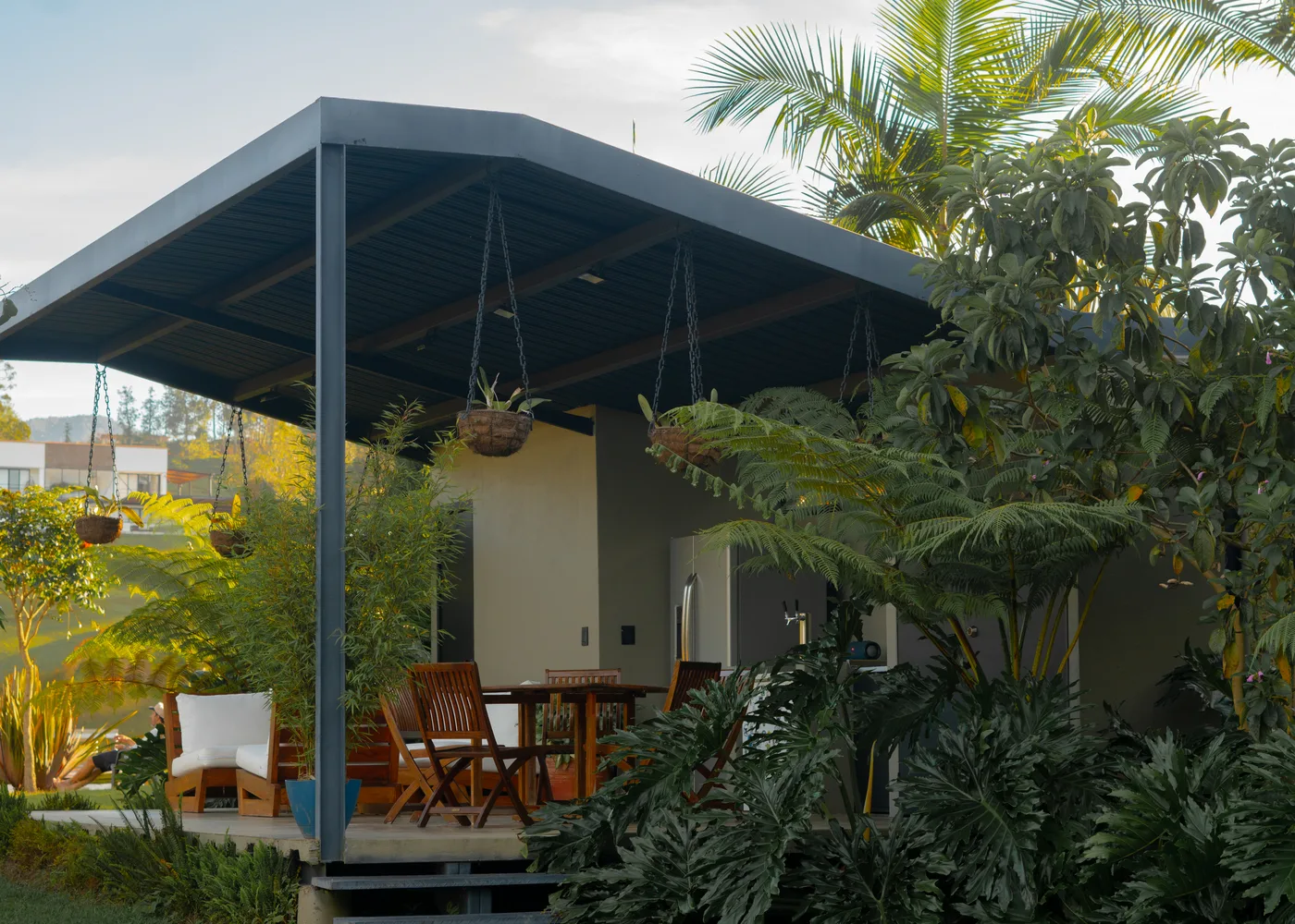 Covered outdoor kiosk with grill and dining table at dusk