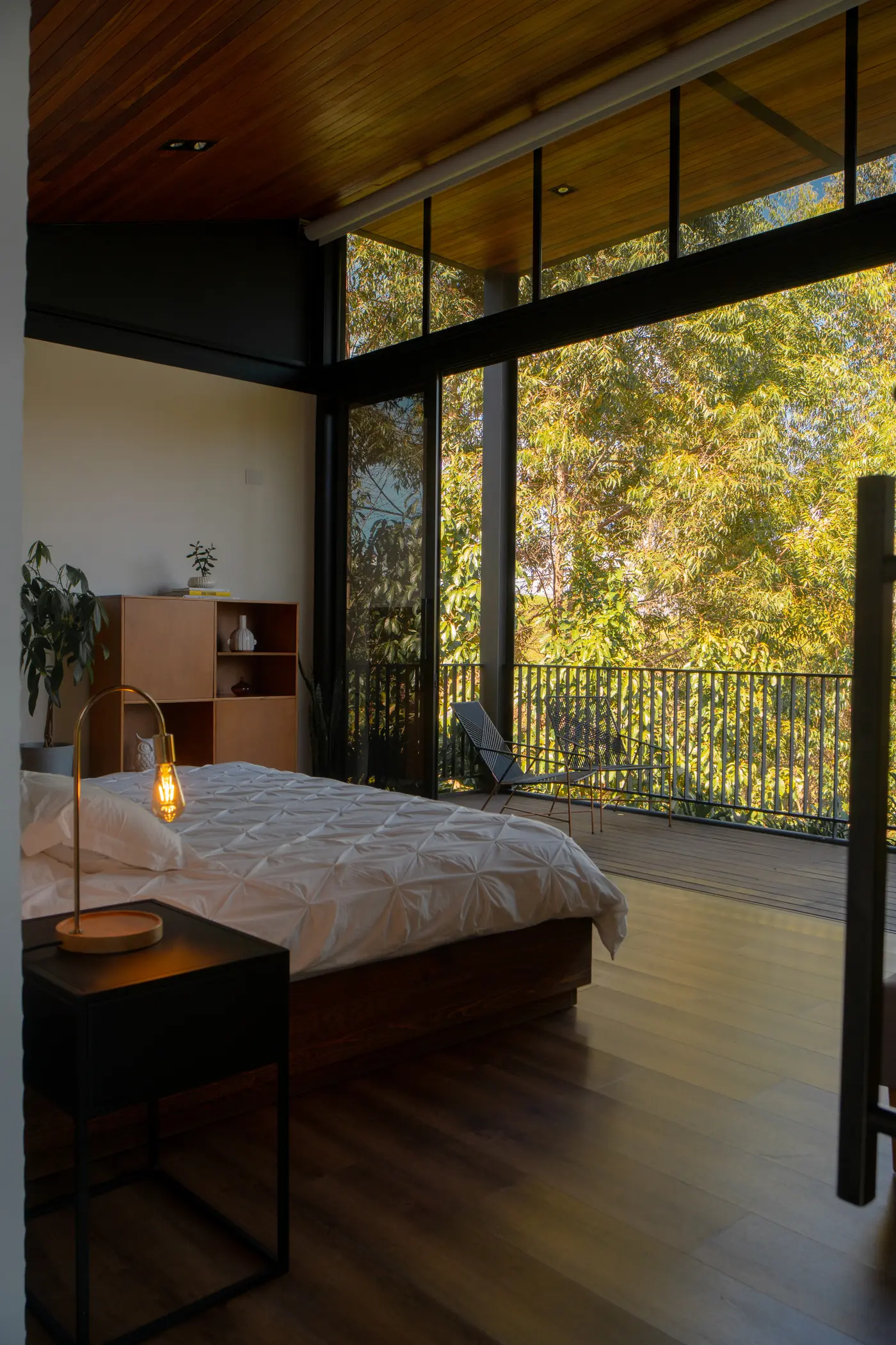 Master bedroom with floor-to-ceiling glass overlooking the lake