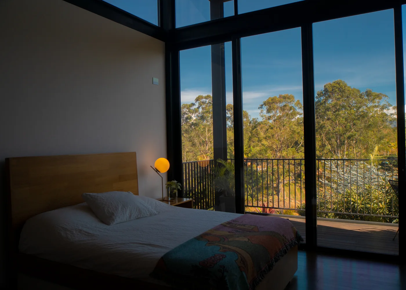 Third master suite bedroom with glass wall at golden hour